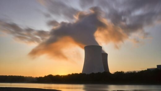 Dramatic image of a nuclear power plant at sunrise with steam rising into a colorful sky.